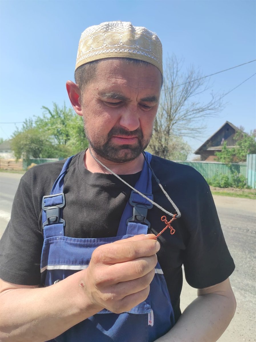 Чоловік показує хрести з дроту, які зробив своїми руками для себе і дружини
